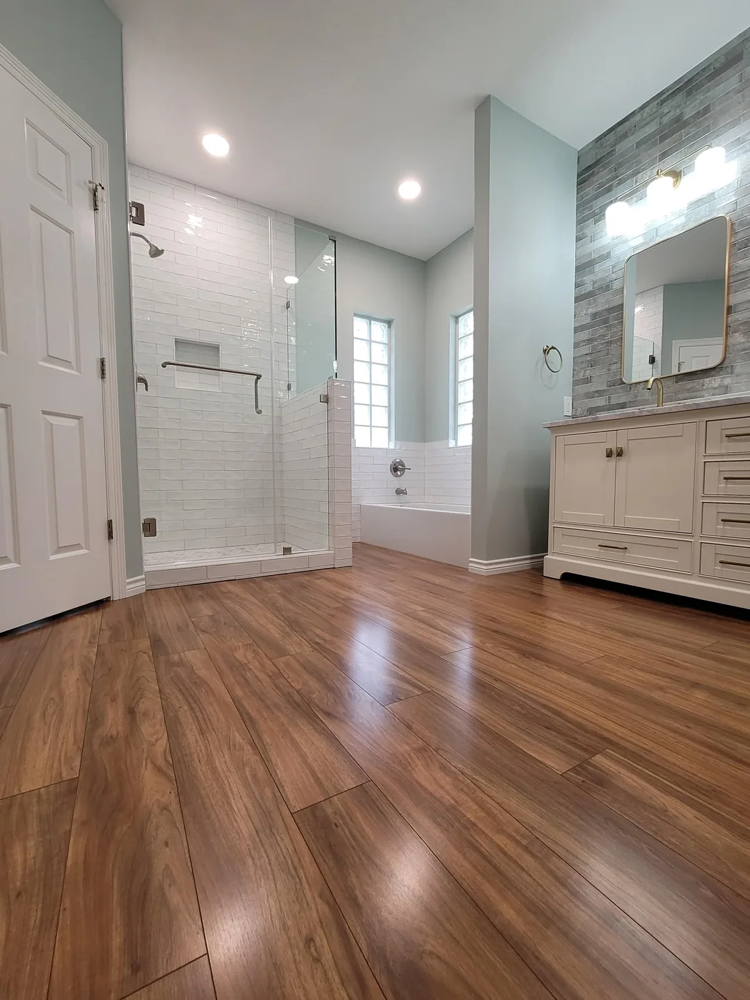 Finished master bathroom with glass shower, soaking tub and wood-look flooring